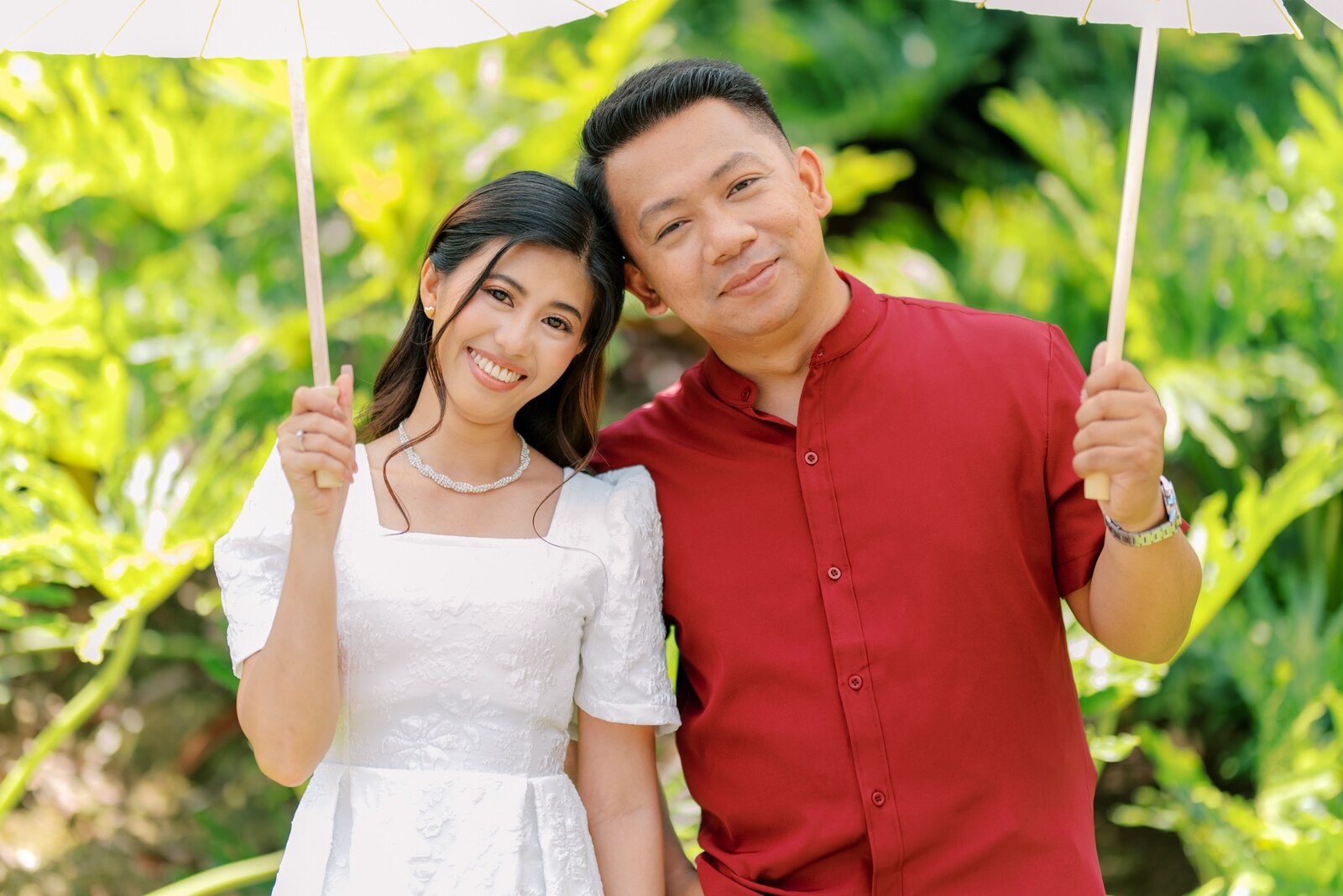 Shelo and Majorie smiling together beneath a white parasol